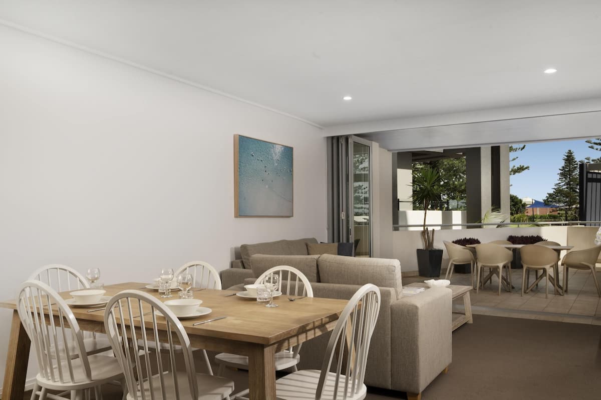A modern living room with a dining area, a sofa, and a view of the outdoors.