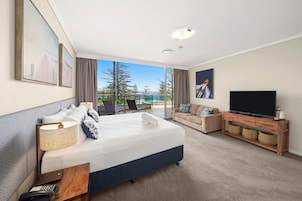 Habitación de hotel con una cama grande, televisión, escritorio y vistas al exterior.