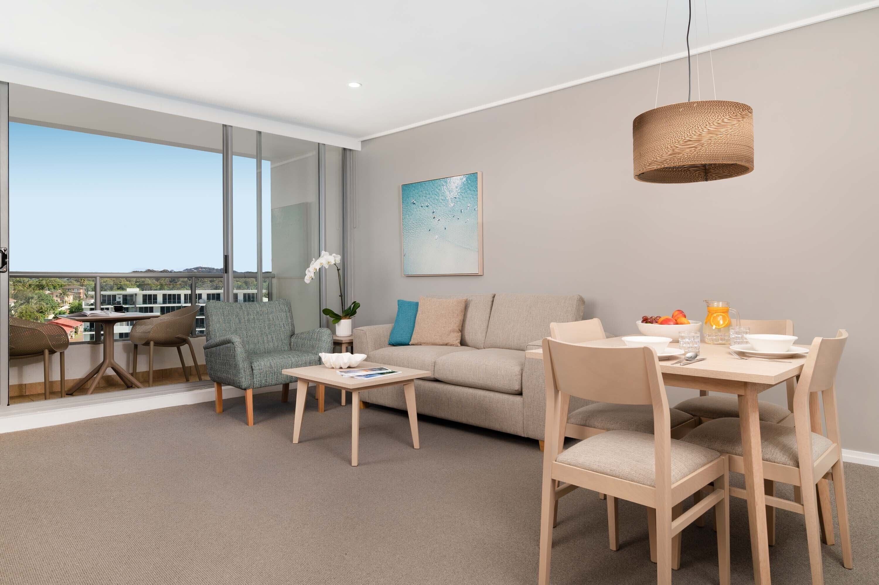 Ein modernes Wohnzimmer mit Sofa, Esstisch, Stühlen und einem großen Fenster mit Blick auf die Stadt.