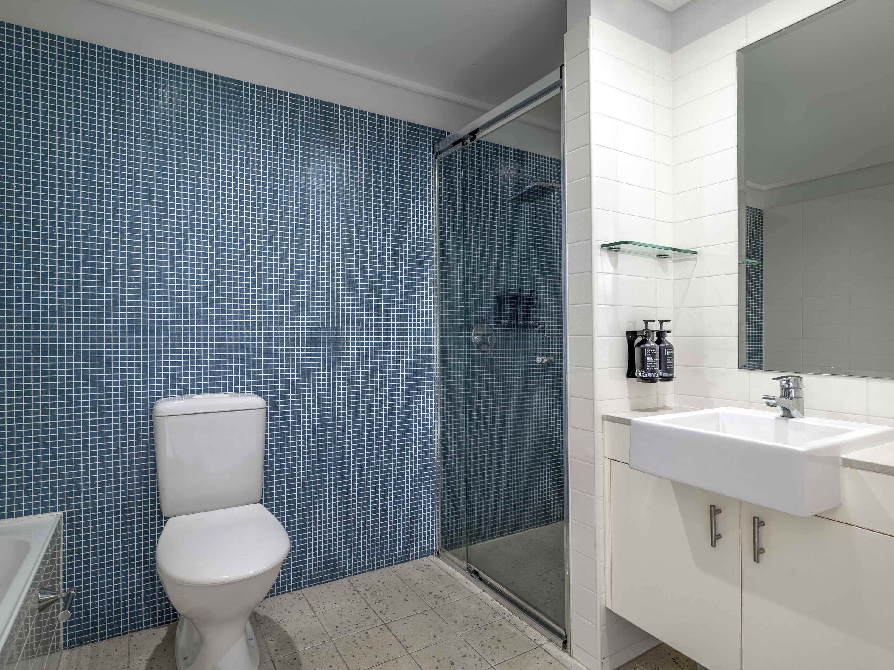 A bathroom with a toilet, a shower with a glass door, a sink, and a mirror.