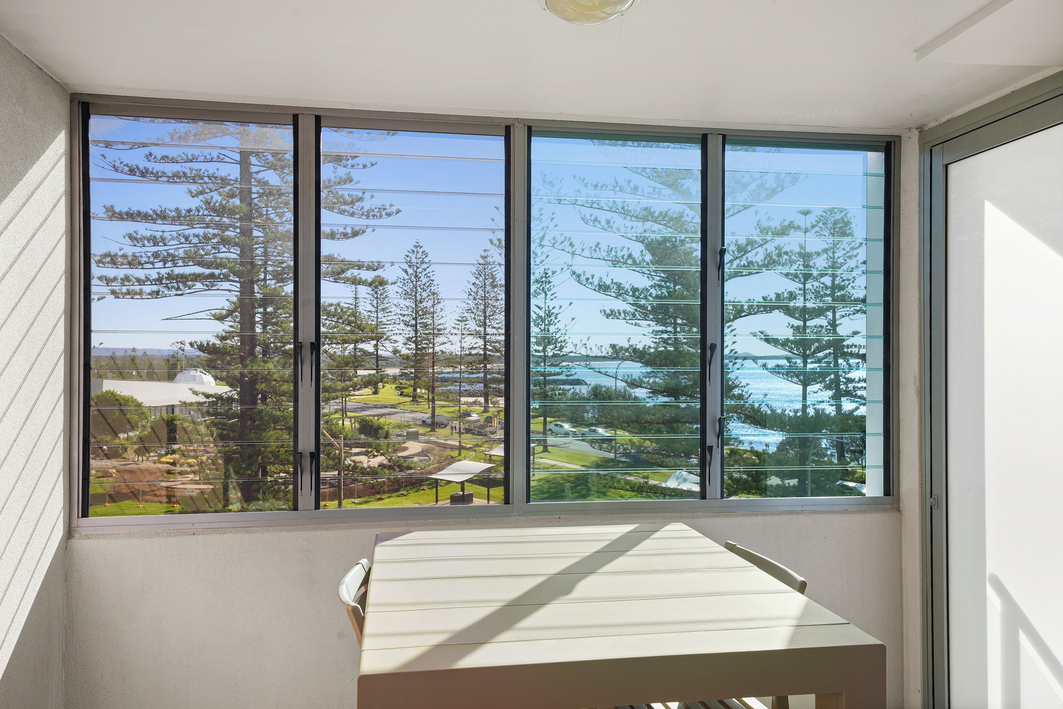A room with a large window offering a view of a landscaped area with trees and a building.