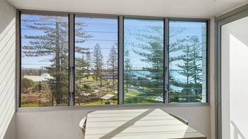 A room with a large window offering a view of a landscaped area with trees and a building.