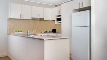 A modern kitchen with white cabinetry, a built-in microwave, and a stainless steel refrigerator.