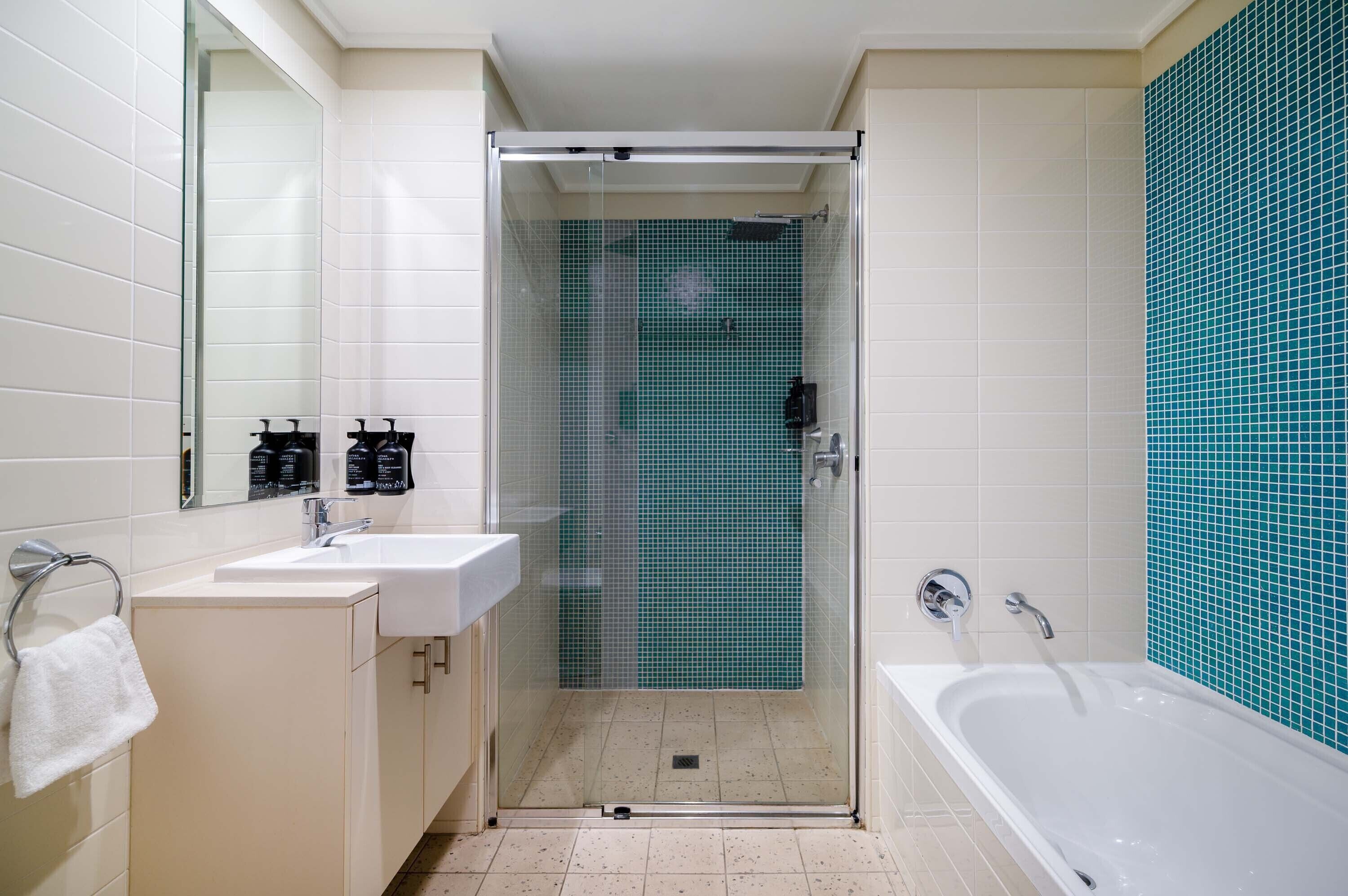 A modern bathroom with a glass-enclosed shower, two sinks, and a bathtub.