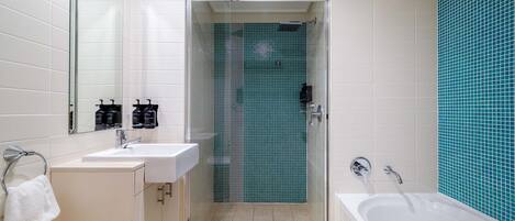 A modern bathroom with a glass-enclosed shower, two sinks, and a bathtub.