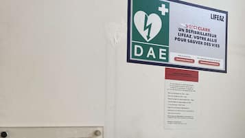 Eine Wand mit einem DAE-Defibrillator, einem Rauchverbotsschild und einem LifeZ-Pulsoximeter.