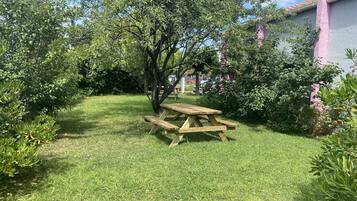 Ein Holztisch für ein Picknick in einem grünen Garten mit Bäumen und Sträuchern.