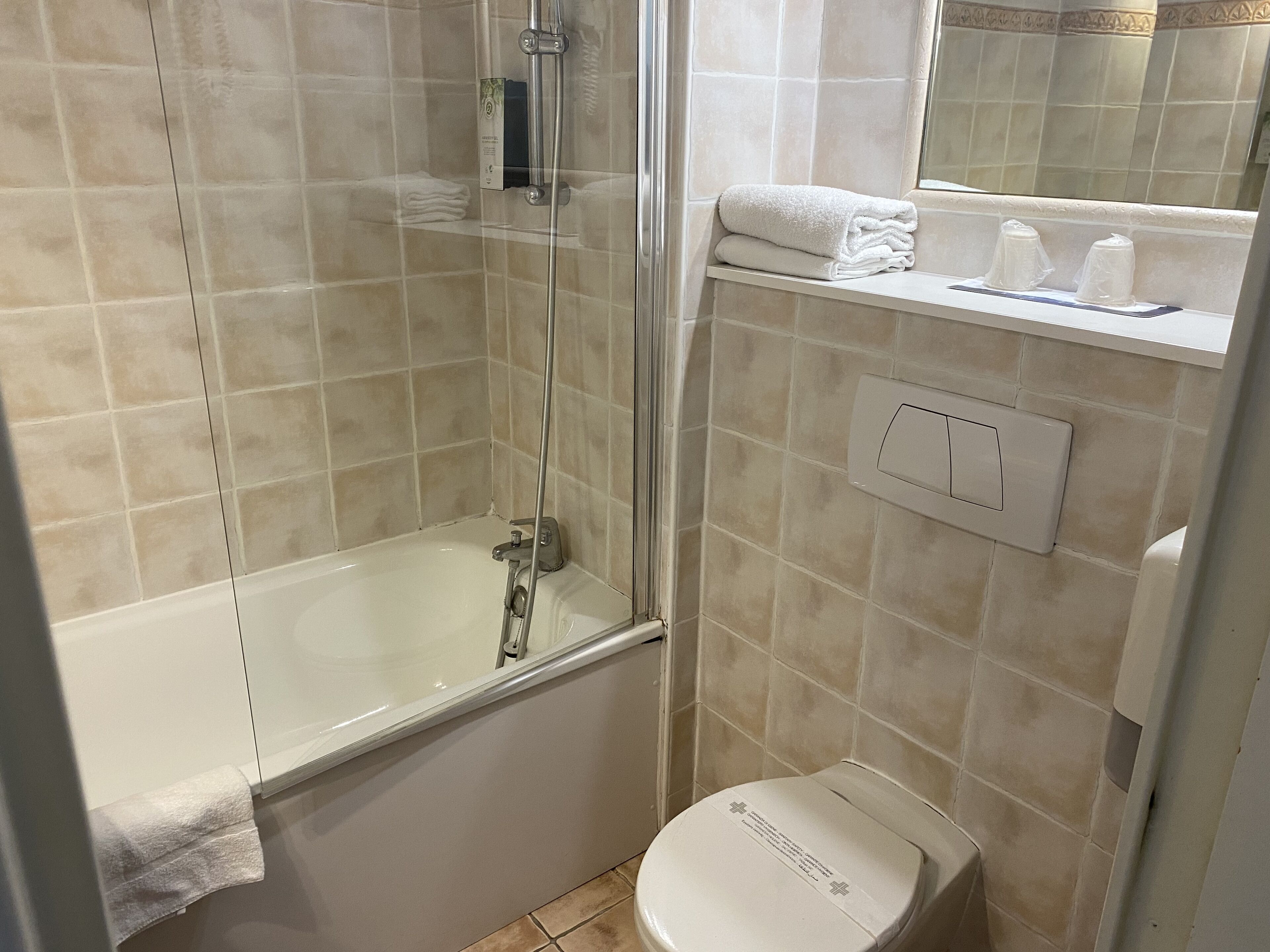 A bathroom with a glass-enclosed shower, a white bathtub, and a toilet.