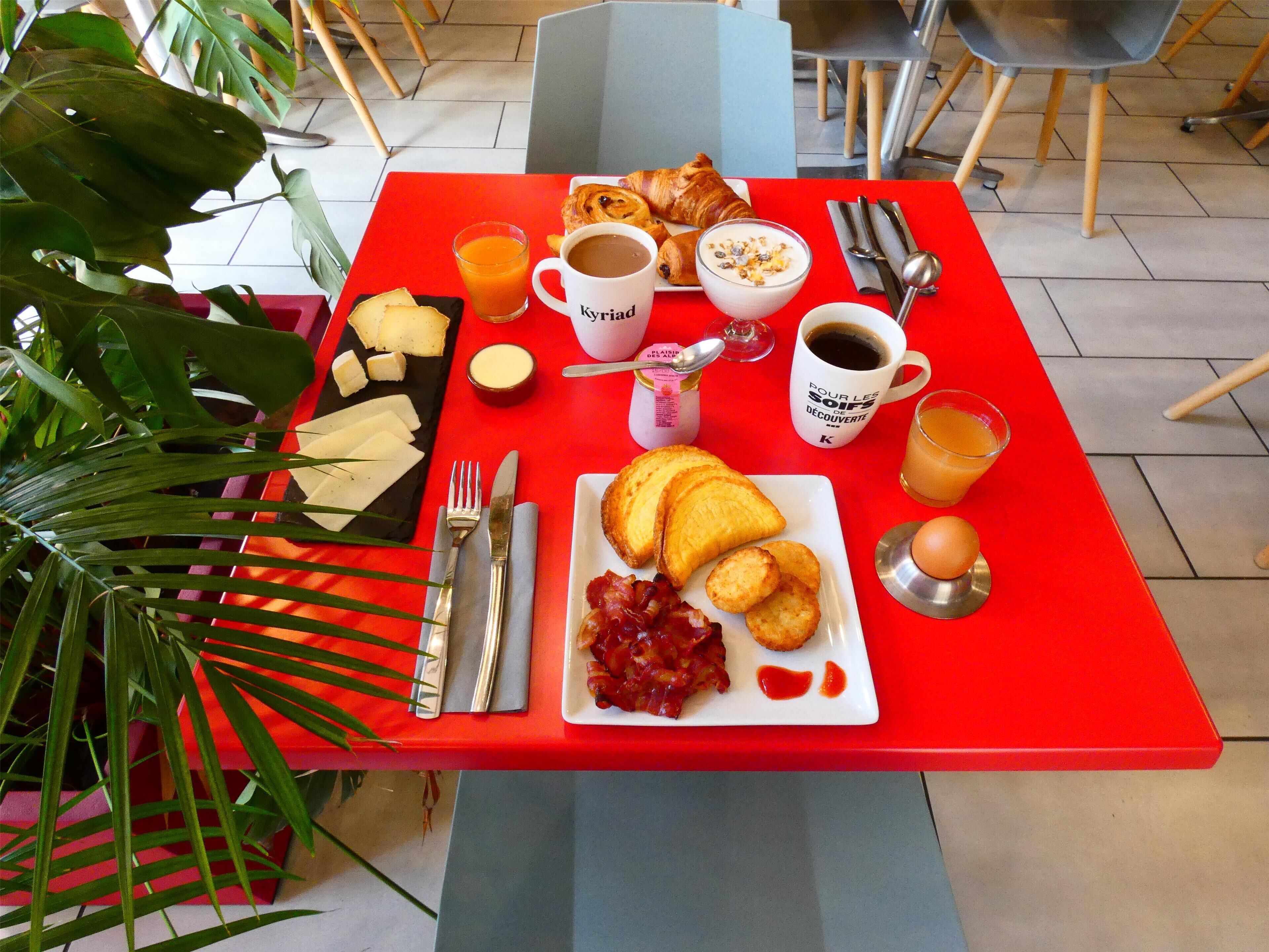 A breakfast table with a variety of food items, including toast, eggs, and a croissant.