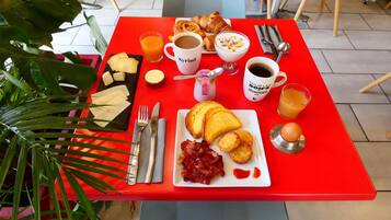 A breakfast table with a variety of food items, including toast, eggs, and a croissant.