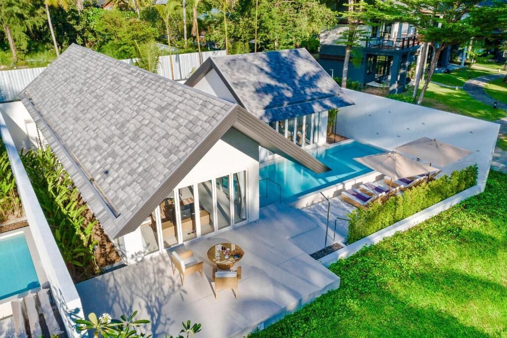 Una casa moderna con piscina, mobiliario exterior y un jardín bien cuidado.