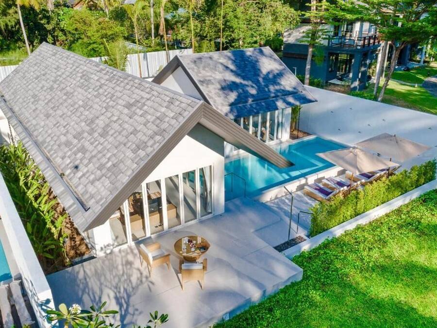 Una casa moderna con piscina, mobiliario exterior y un jardín bien cuidado.