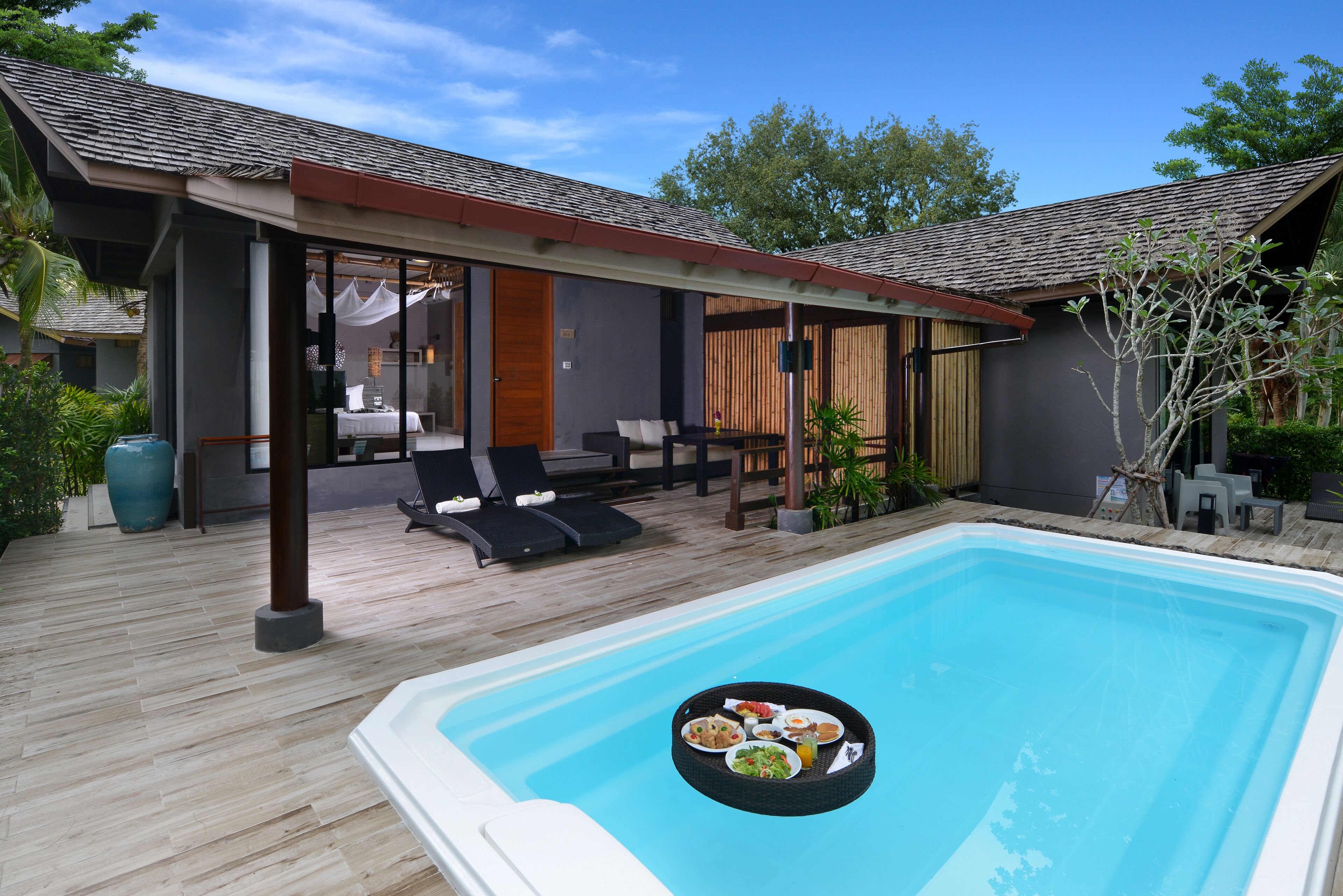 Uma área de piscina moderna ao ar livre, com espaço coberto para relaxar e um espaço para refeições.