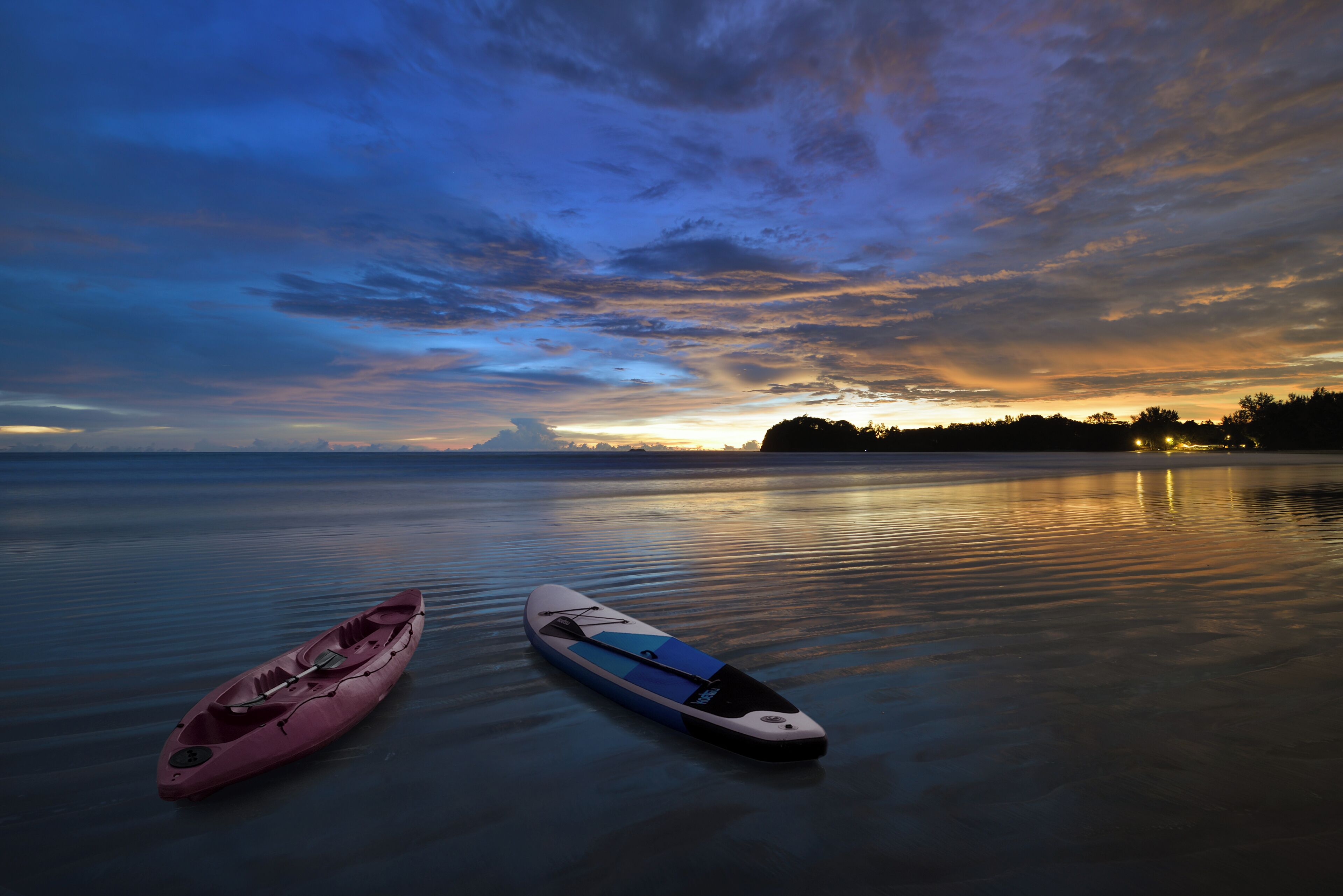 Two kayaks on calm water with a sunset in the background.