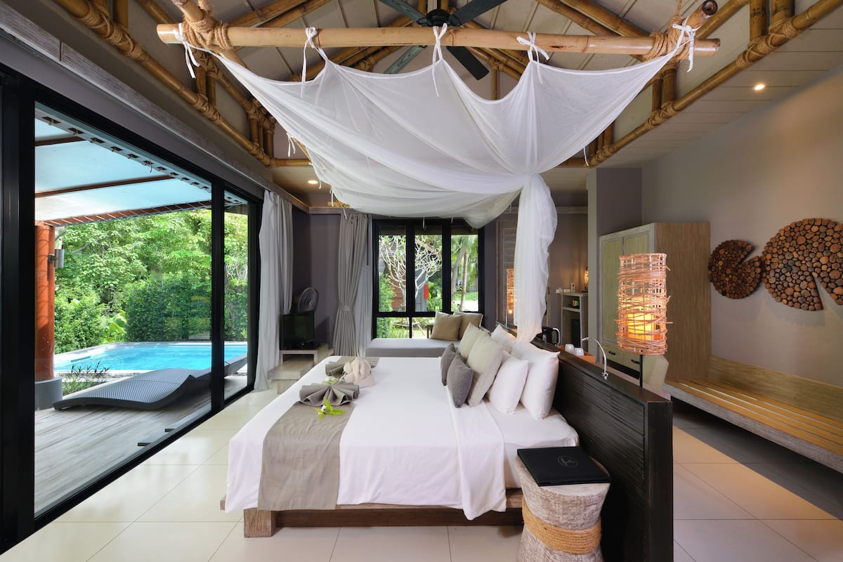 A spacious bedroom with a large bed, a view of a swimming pool, and a ceiling fan.