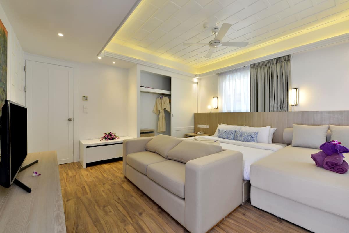 A modern hotel room with a sofa, a bed, a desk, and a wardrobe.
