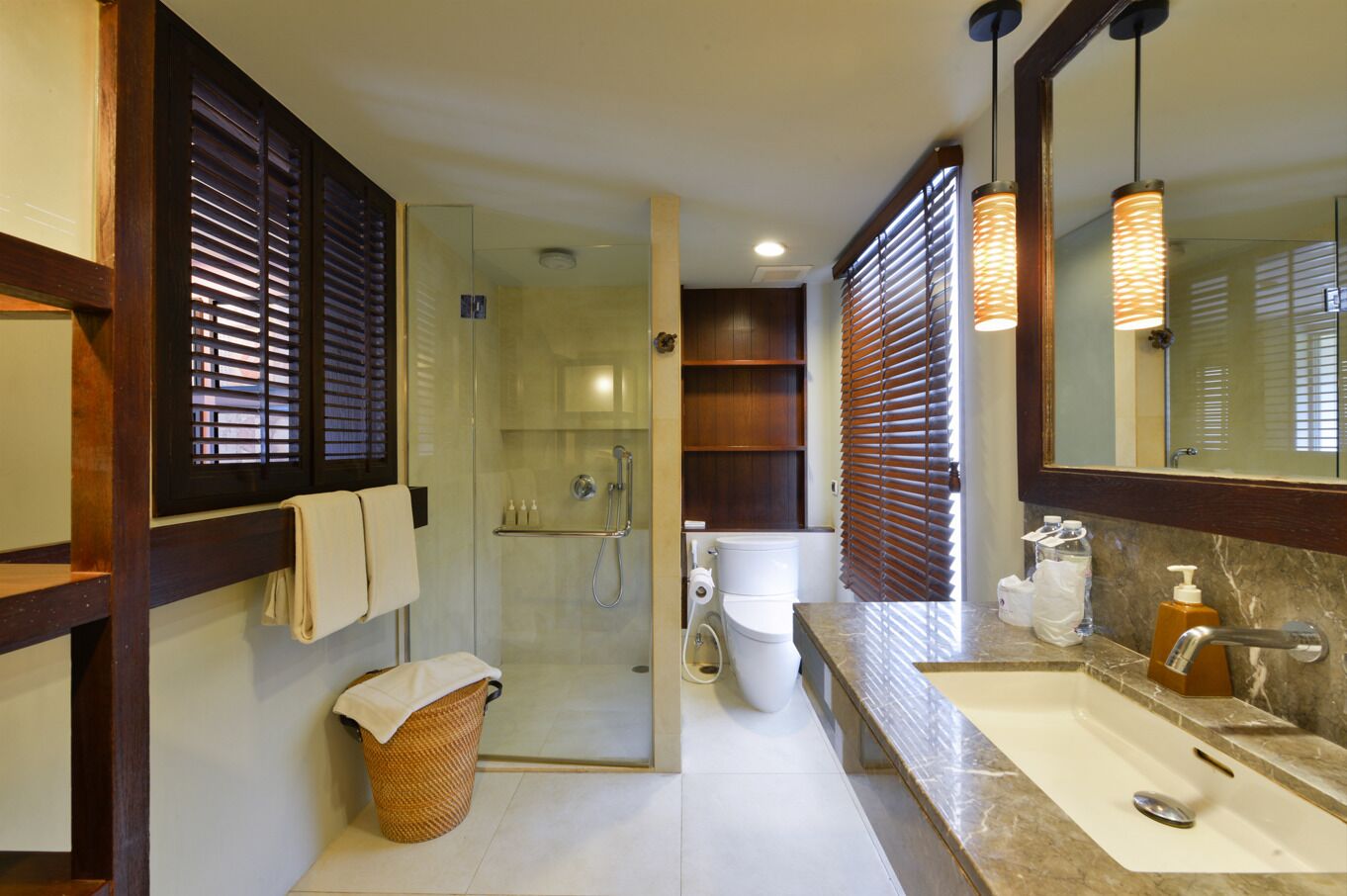 Un baño moderno con ducha de vidrio, inodoro blanco y lavamanos de mármol.