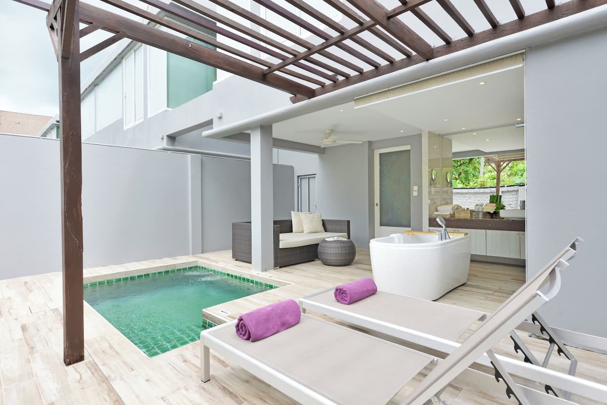 A modern outdoor pool area with lounge chairs, a hot tub, and a seating area.