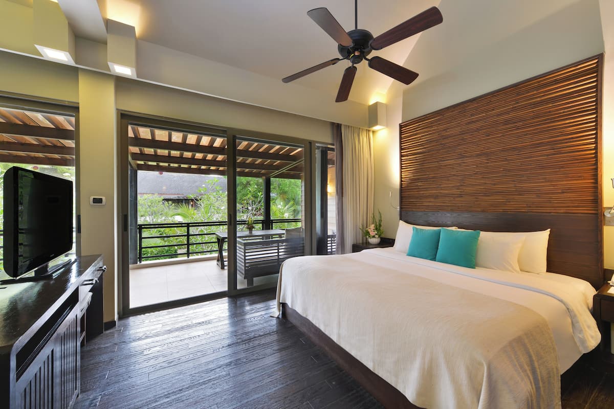 A spacious bedroom with a large bed, a ceiling fan, and a TV on a dresser.