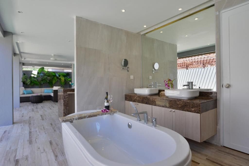 Un baño moderno con una bañera grande, dos lavamanos y un espejo amplio.