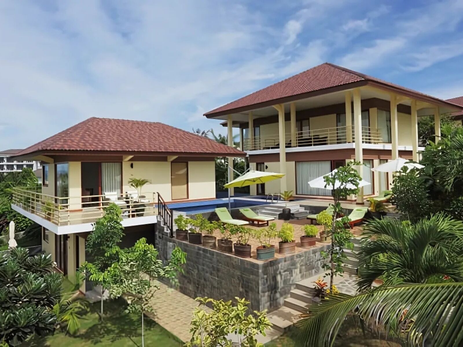 A two-story villa with a swimming pool, outdoor seating, and lush greenery.