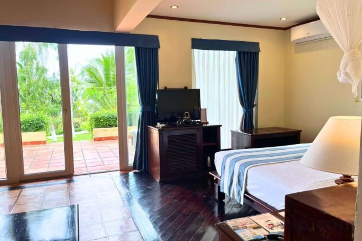 Habitación de hotel con cama, escritorio, televisión y vistas al exterior.