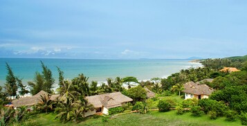 Un village côtier aux maisons aux toits de chaume, entouré d’une végétation luxuriante, et offrant une vue sur la mer.