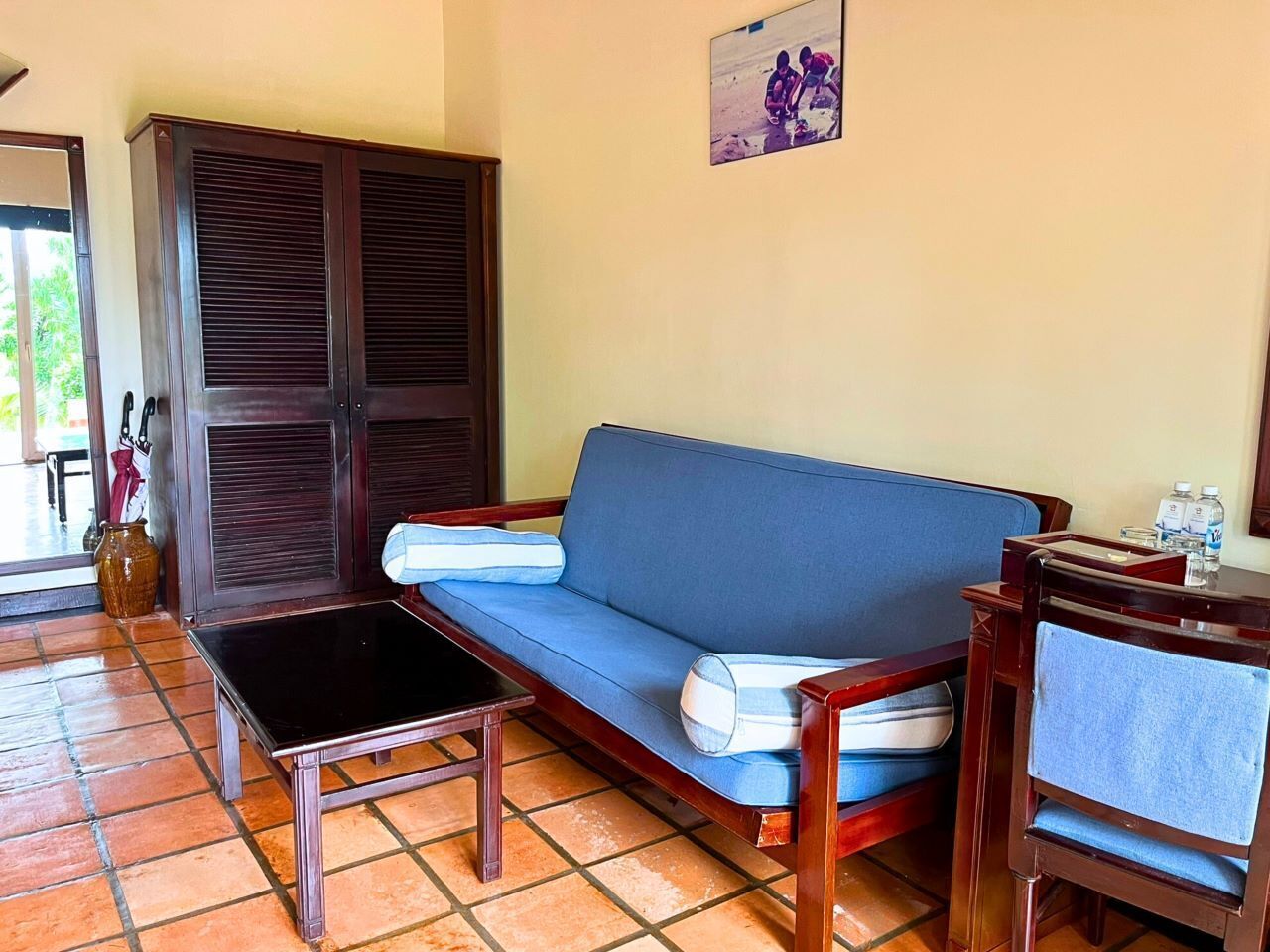 Een kamer met een blauwe bank, een houten tafel en een kast.