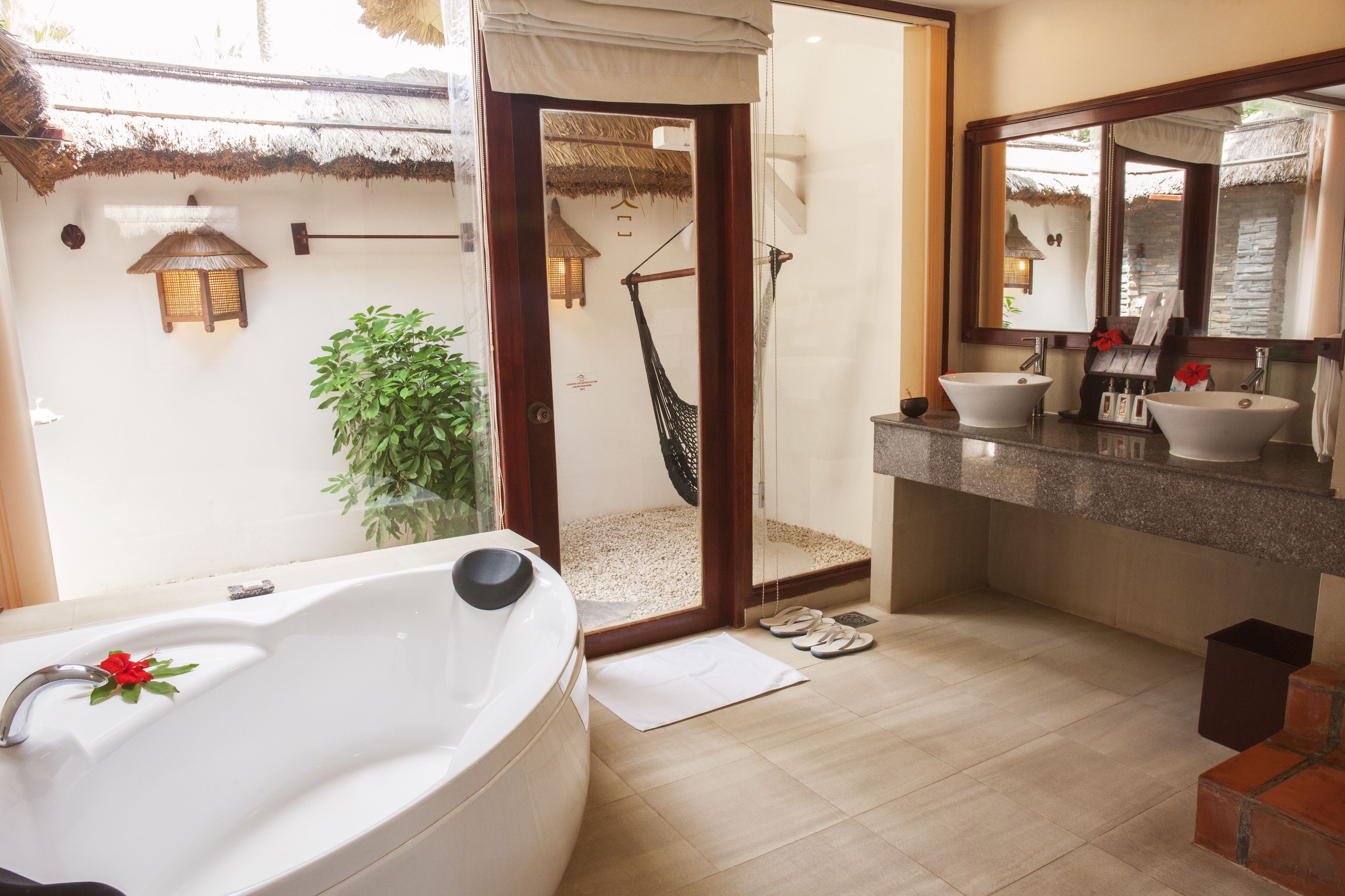 Un baño con una bañera grande, dos lavamanos, zona de ducha y un espejo.