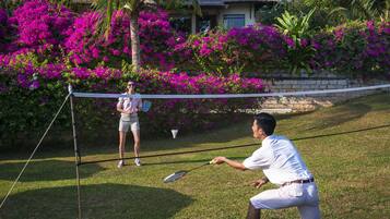 Enjoy a game of tennis surrounded by lush gardens and a residential backdrop.