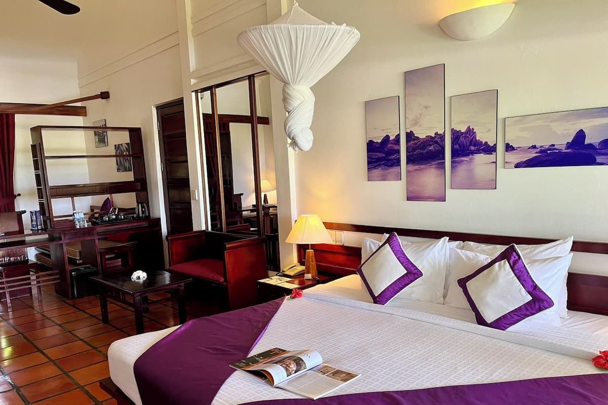 Une chambre d’hôtel avec un grand lit, un bureau, une chaise et une bibliothèque.