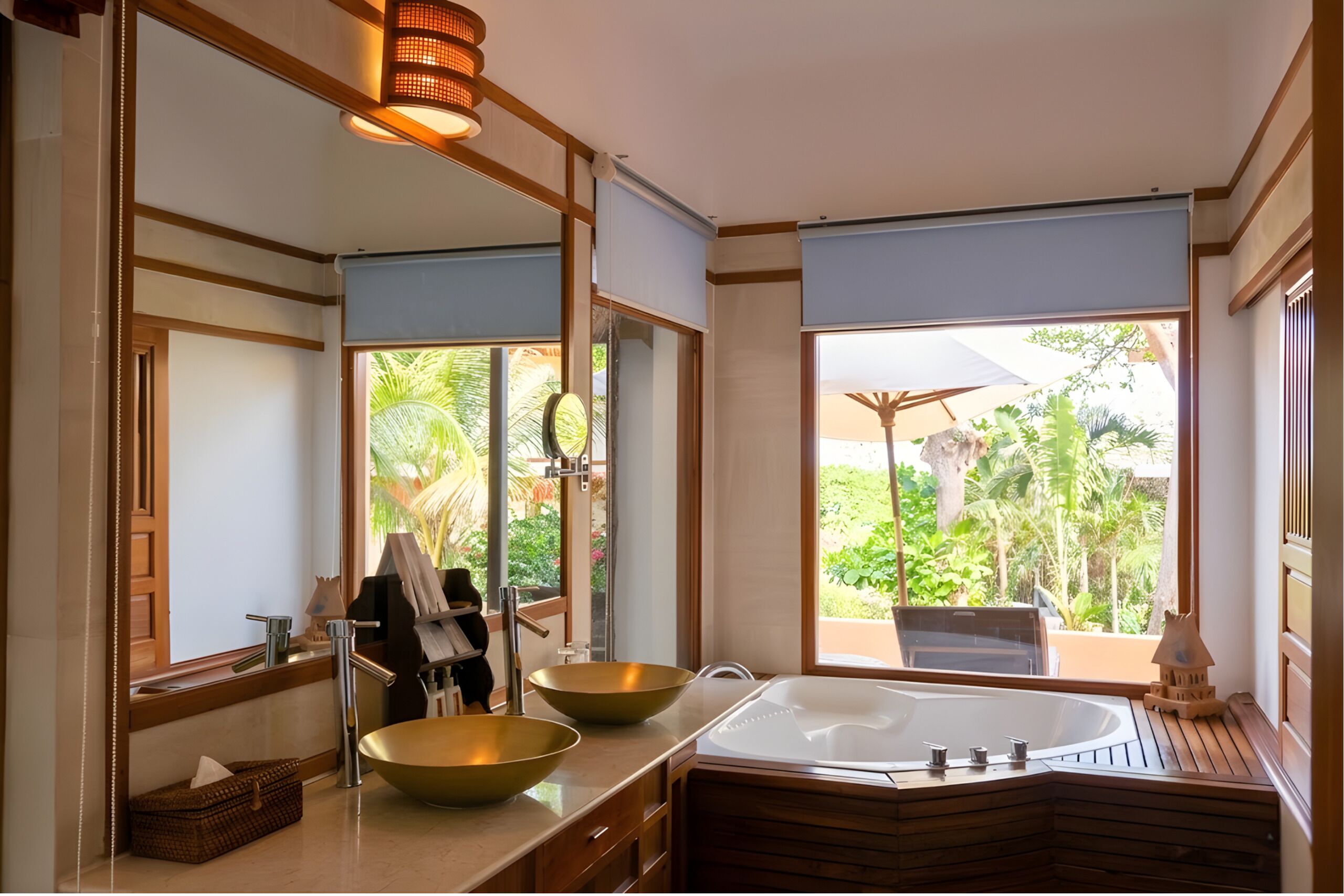 A bathroom with a large mirror, a wooden vanity, a bathtub, and a view of a lush garden.