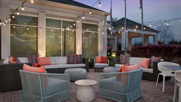 Un patio al aire libre con arreglos de asientos, luces colgantes y una sección cubierta.