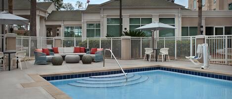 Alberca al aire libre, sombrillas en la alberca y camastros