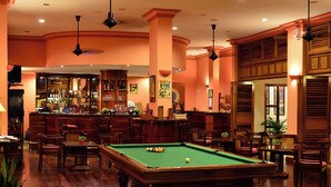 A billiards room with a pool table, bar area, and wooden furniture. - Victoria Can Tho Resort (Can Tho)