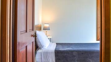 A room with a bed, a nightstand with a lamp, and a wooden door.