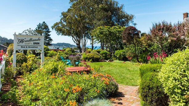 Un sentier de jardin mène à l’établissement Headlands Inn, et une pancarte indique qu’il propose des services d’hébergement et de petit-déjeuner.
