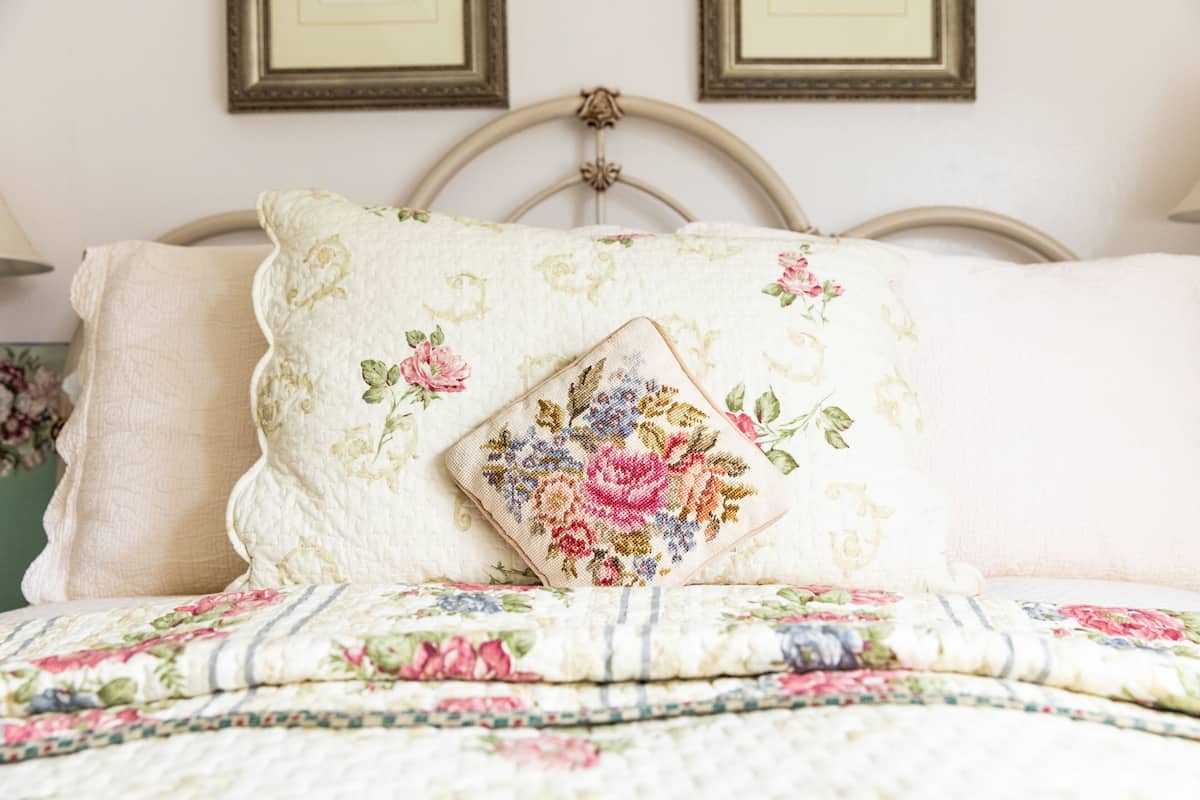 Ein Bett mit floraler Bettwäsche und einem Zierkissen.
