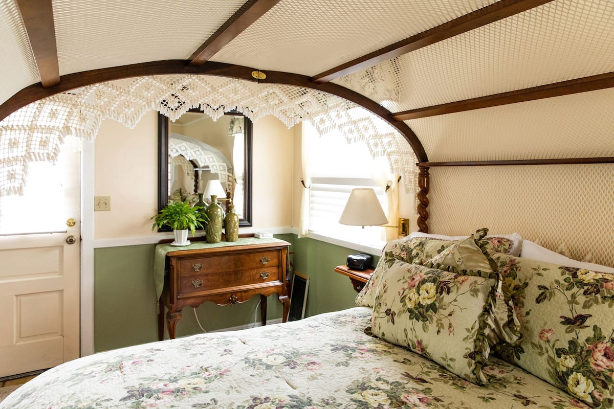 Ein Zimmer mit einem Bett, einem Schrank, einem Spiegel und einem Fenster.