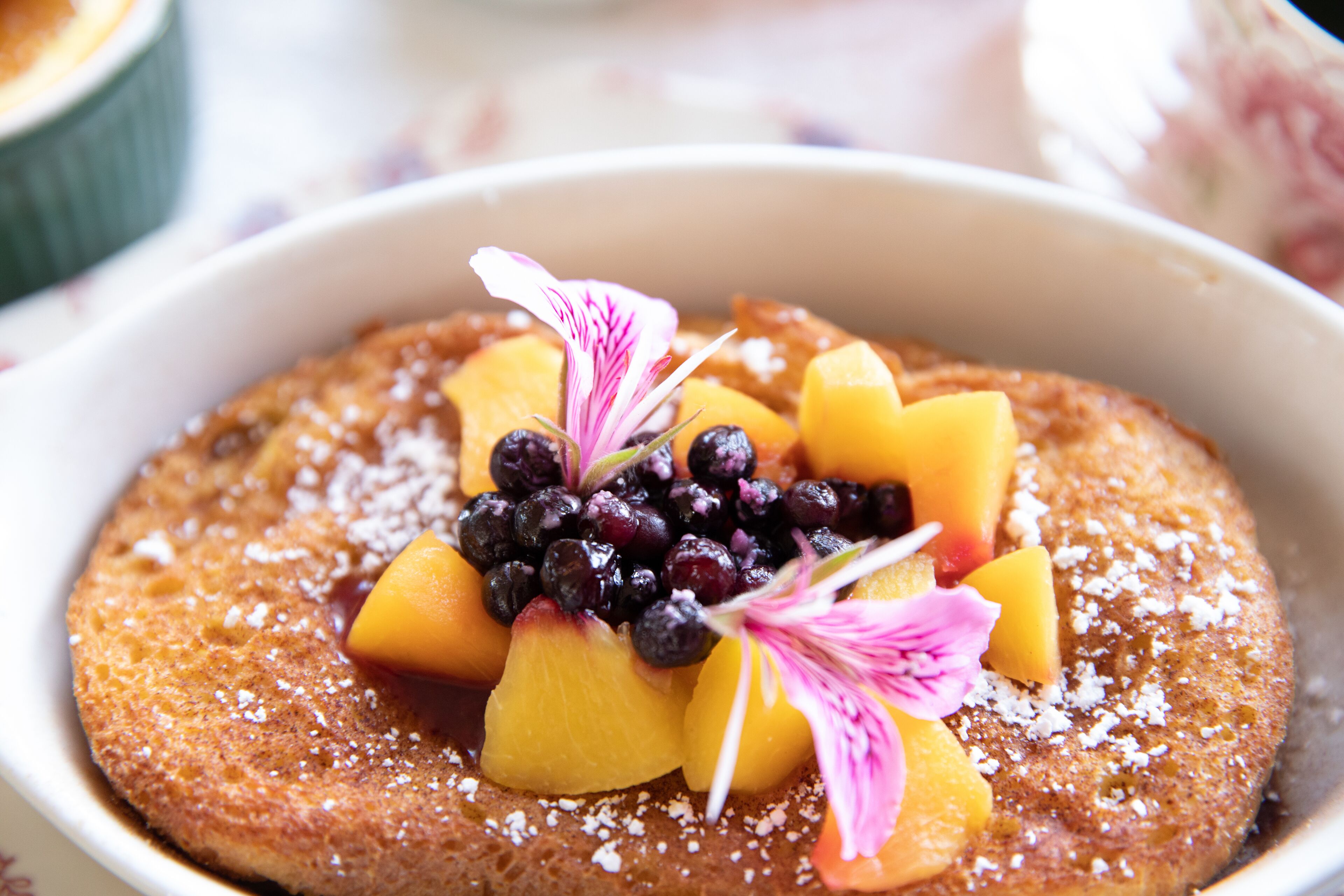 Ein Dessert mit Früchten und einer Blüte, serviert in einer weißen Schüssel.