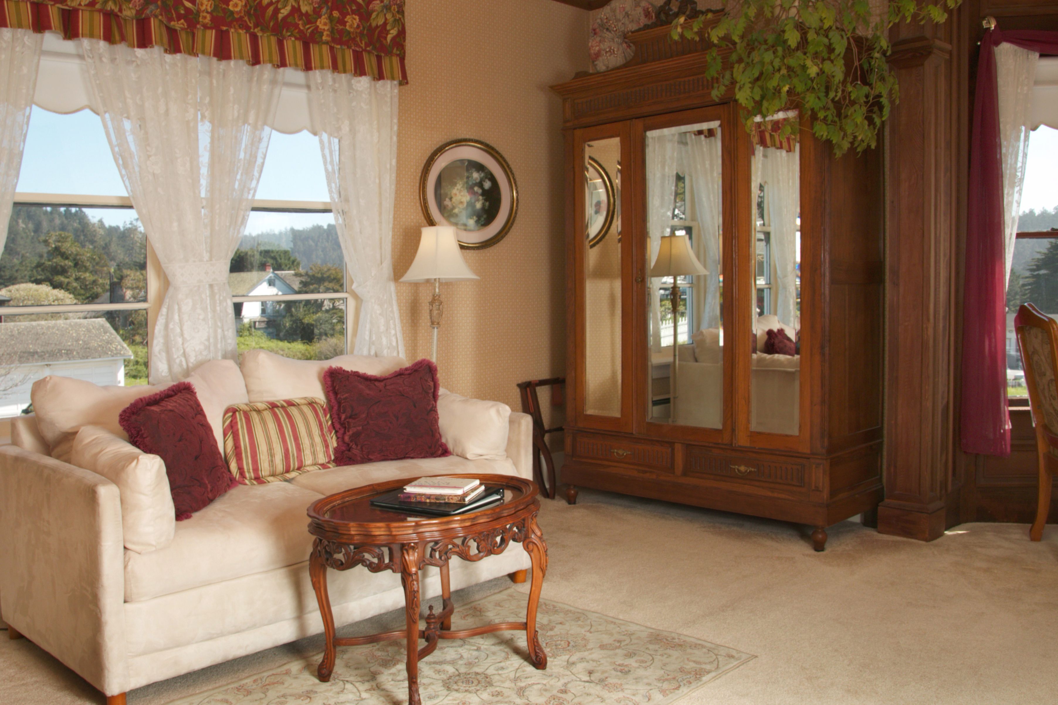 A living room with a white sofa, red and beige pillows, a wooden cabinet, and a round wooden coffee table.