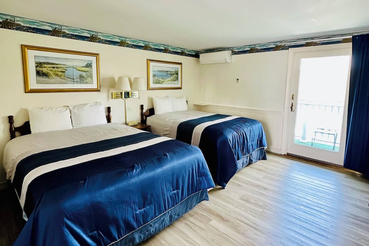 A hotel room with two beds, a large window, and a view of the outdoors.