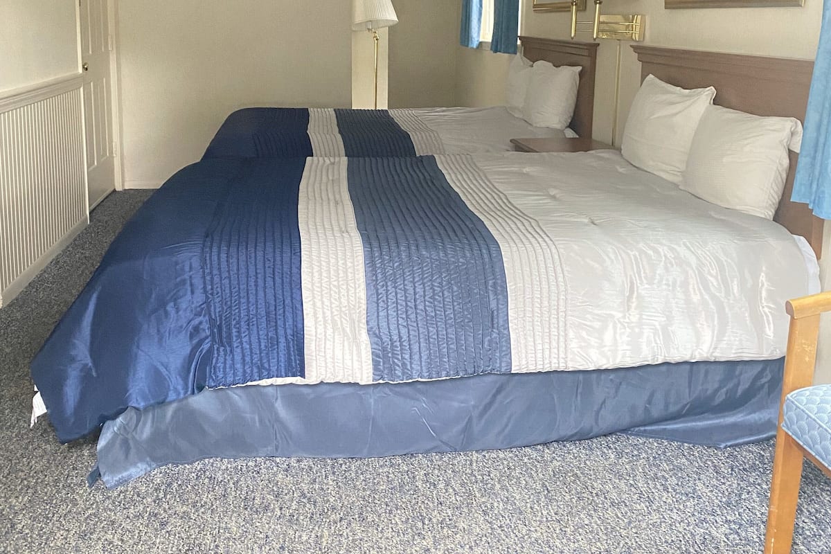 A hotel room with a large bed, a nightstand with a lamp, and a painting on the wall.