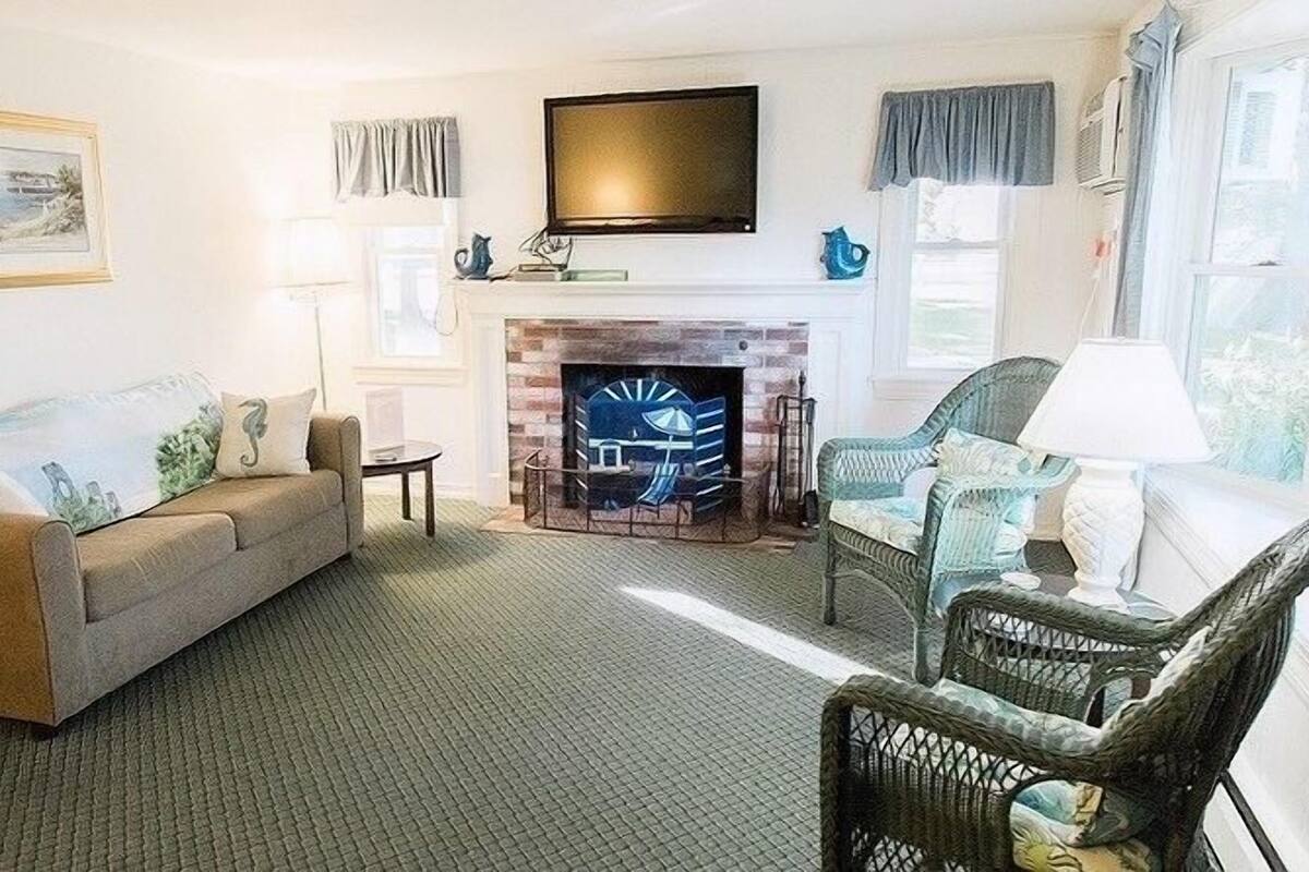 A living room with a sofa, a chair, a fireplace, and a television.