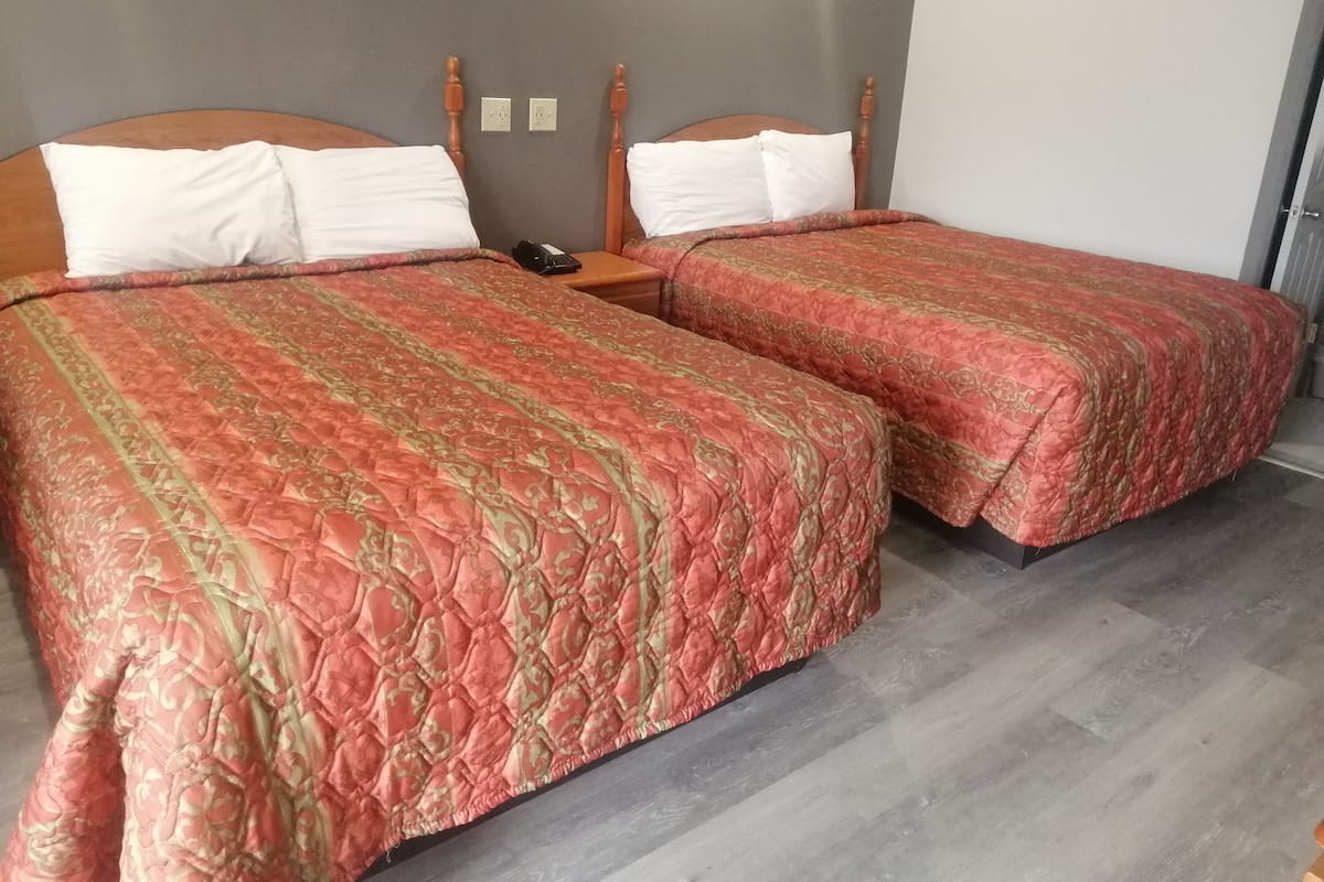 A double room with two beds, each with a wooden headboard and white pillows.