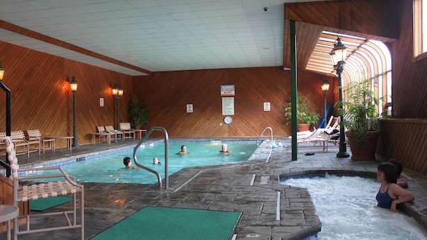 Ein hallenbad mit mehreren Bahnen, Liegestühlen und einem Whirlpool-Bereich.