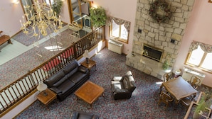 Eine großzügige Lobby mit Kamin, Ledersofas, einem Kronleuchter und einem gemusterten Teppich.