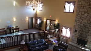 Eine geräumige Lobby mit Ledersofas, einem Chandelier, einem Kamin aus Stein und Blick auf die obere Etage.