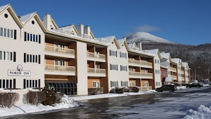 Ein Nordic Inn Hotel mit mehreren Etagen, Balkonen und einem schneebedeckten Berg im Hintergrund.