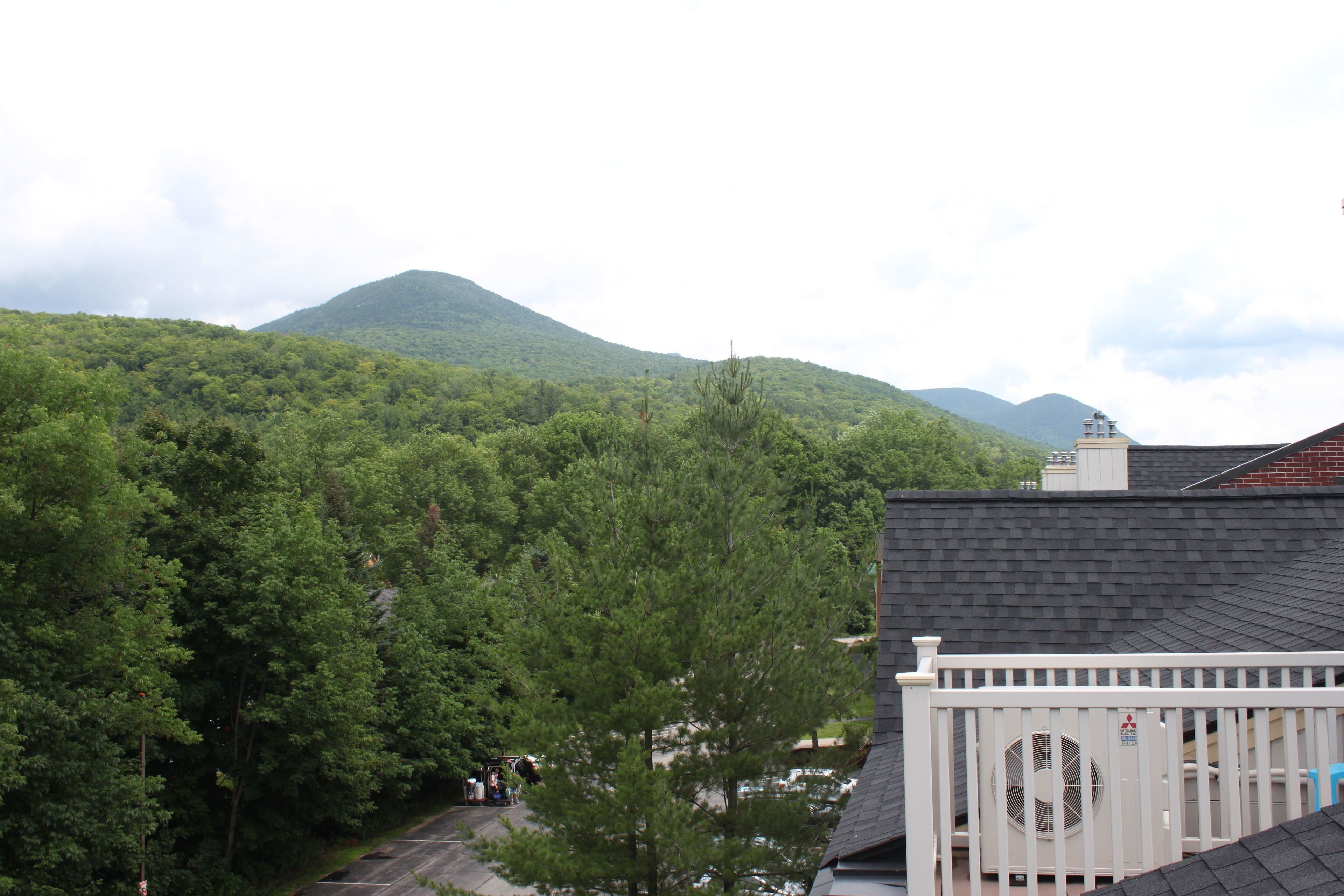 A residential area with a view of a mountain, a white fence, and a house with a dark roof.